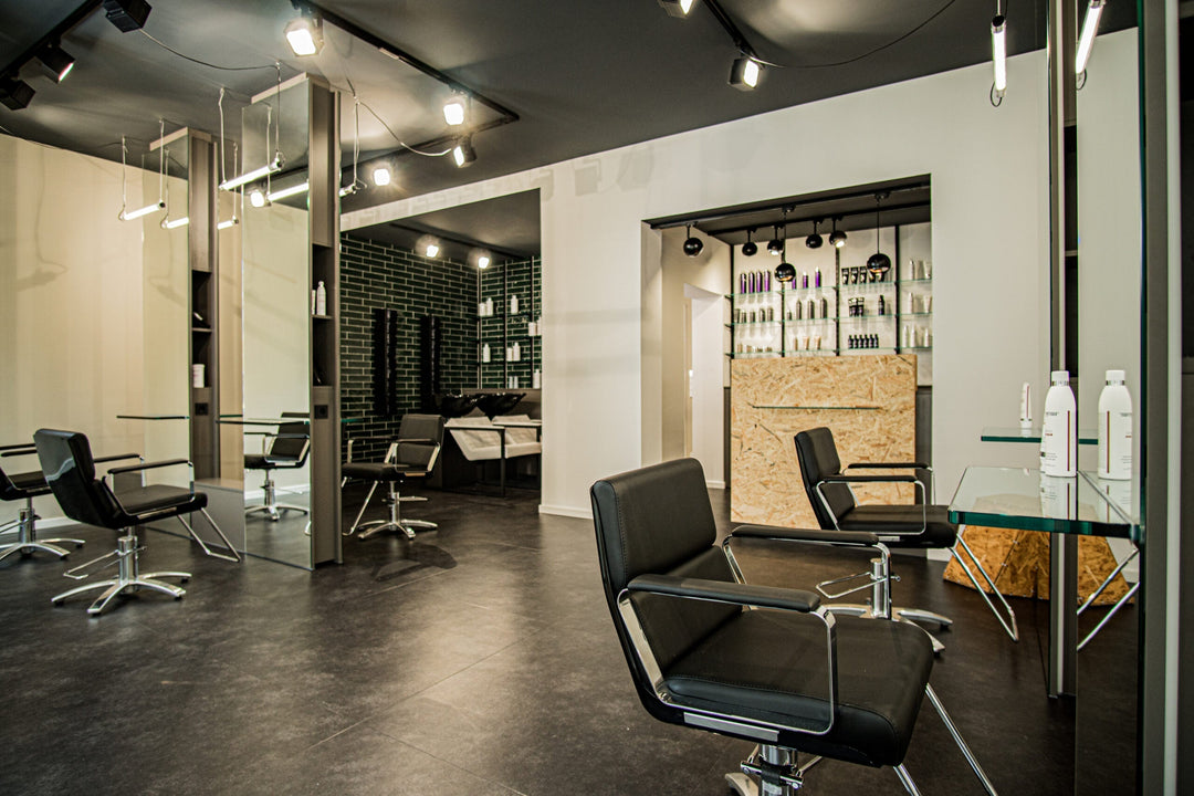 Friseursalon EPICENE: Takara Belmont Friseurstühle Adria in Schwarz, Glasspiegel und Travertin-Theke